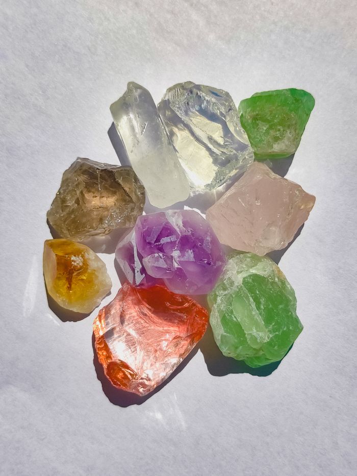 A vibrant collection of colorful crystals arranged in bright sunlight on a white surface.